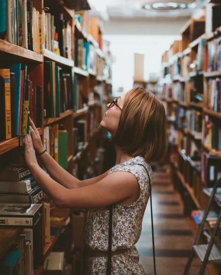 A woman searching for a book in a library